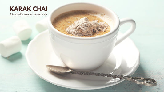 A creamy cup of Karak Chai topped with chai tea powder, served in a white teacup with a twisted silver spoon, showcasing the rich and authentic flavor of Karak Chai by Chai Hai.